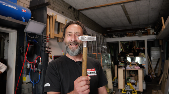 Simon Berger, Schweizer Künstler, in seinem alten Atelier mit seinem ersten Hammer. Herbst 2025.
