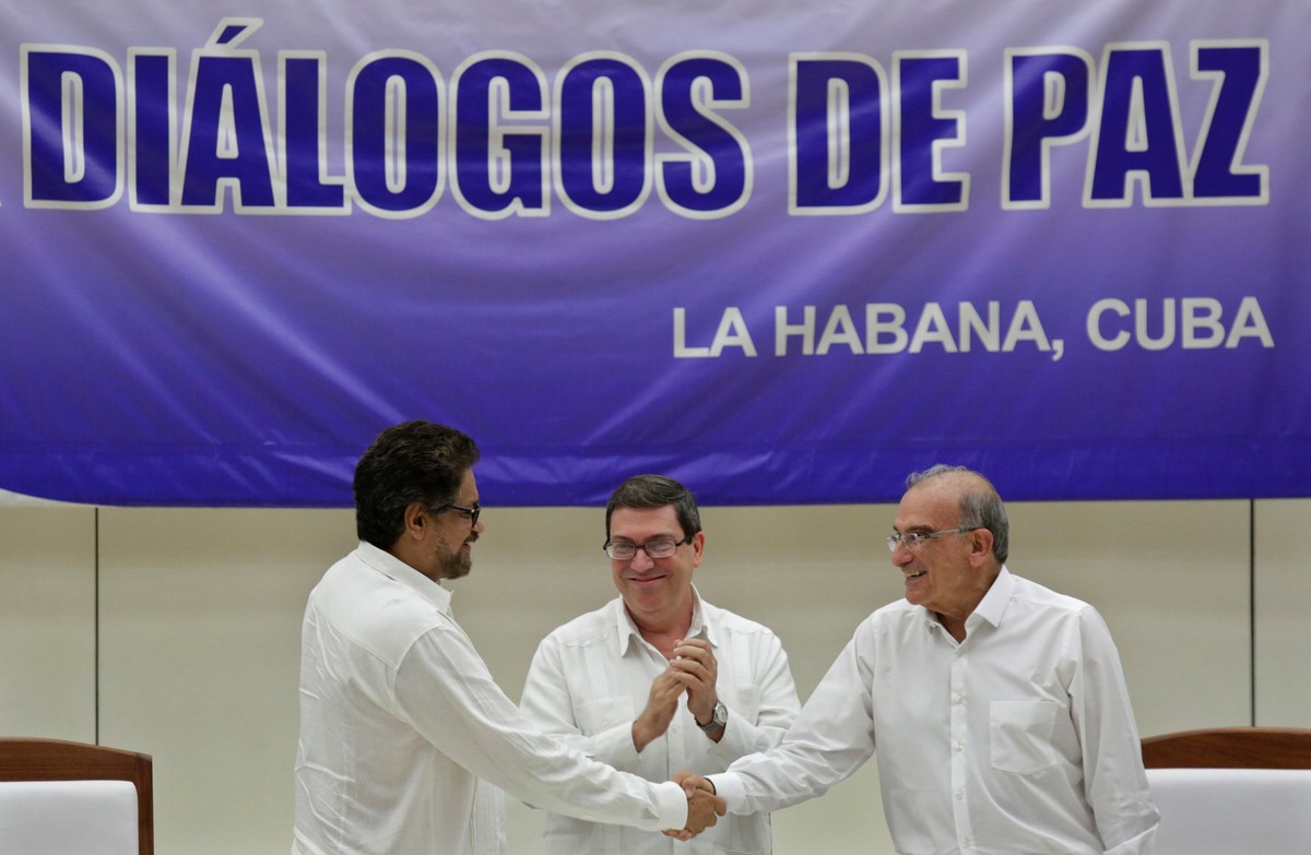 Colombia's FARC lead negotiator Ivan Marquez (L) and Colombia's lead government negotiator Humberto de la Calle (R) shake hands while Cuba's Foreign Minister Bruno Rodriguez looks on, a ...