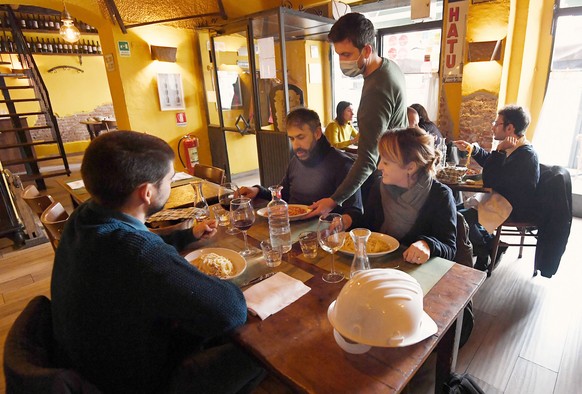 epa08979835 A waiter wearing a face mask serves some customers in a restaurant at lunch time in Milan, Italy, 01 February 2021. As many as 293,000 bars, restaurants, pizzerias and agritourism that sur ...