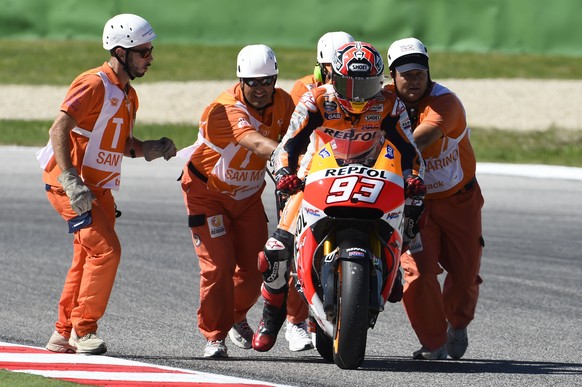 Streckenposten helfen dem gestürzten Marquez wieder auf die Maschine.