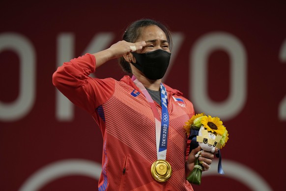 Hidilyn Diaz of Philippines gestures on the podium as she listen to the national anthem after winning the gold medal in the women's 55kg weightlifting event, at the 2020 Summer Olympics, Monday, July  ...