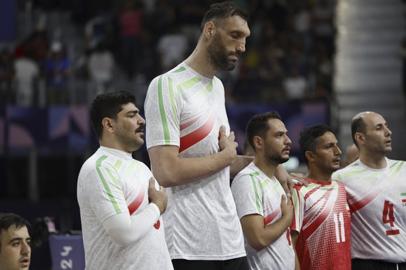 Irans&#039;s Morteza Mehrzadselakjani, fourth from right, stands with his teammates on the men&#039;s sitting volleyball team as the Iranian national anthem plays before their preliminary game against ...
