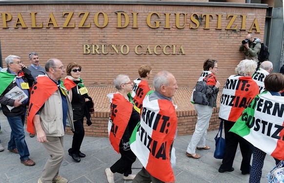epa04744683 Relatives of victims carry Italian flags with the slogan: 'Eternit: Justice!'  as they gather outside the Palace of Justice in Turin, Italy, May 12, 2015, ahead of a first preparatory…