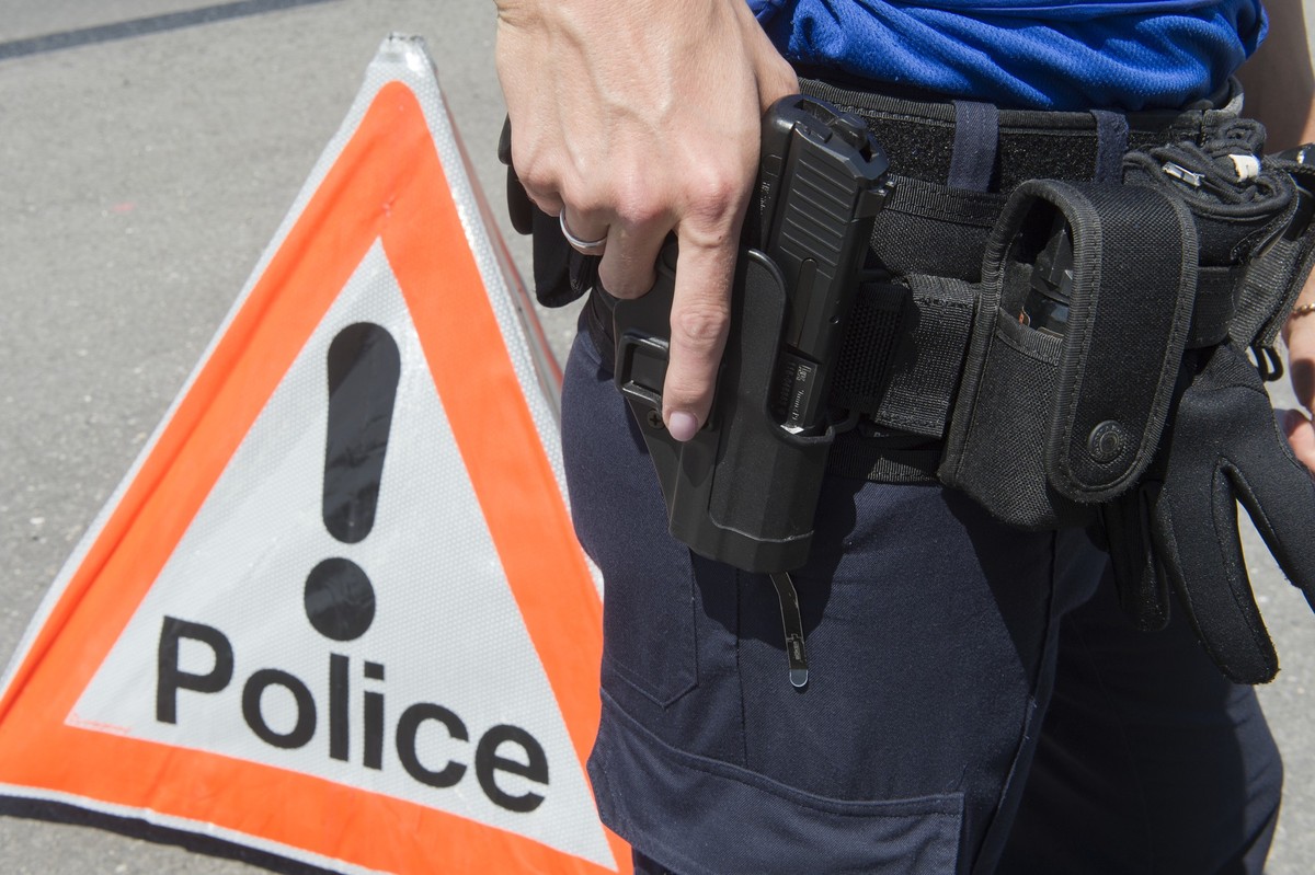 Un policier de la Police cantonale neuchateloise tient son pistolet devant un signe police, le 5 juin 2015, a Neuchatel. (KEYSTONE/Sandro Campardo) 

Ein Polizist der Kantonspolizei Neuenburg greift n ...