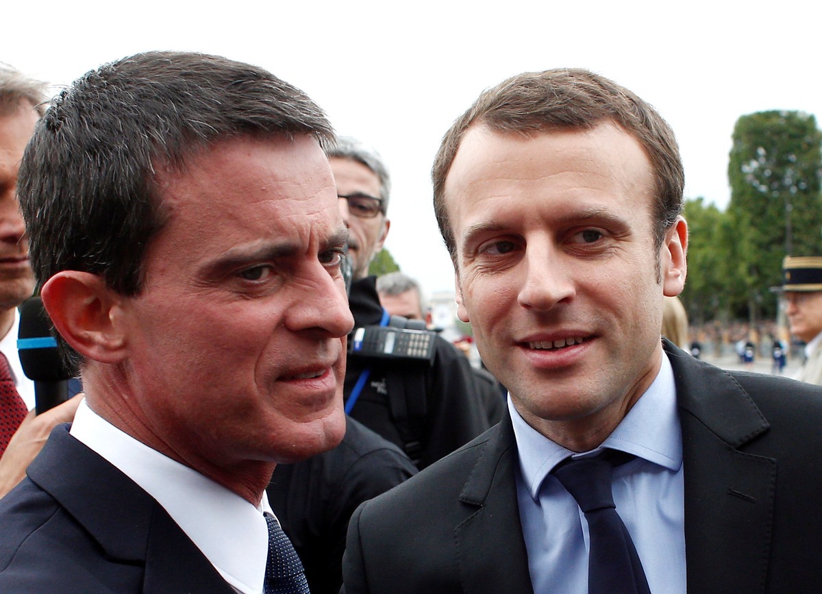 FILE PHOTO: French Prime Minister Manuel Valls (L) welcomes Economy Minister Emmanuel Macron on the Champs-Elysees Avenue before the Bastille Day military parade in Paris, France, July 14, 2016. REUTE ...