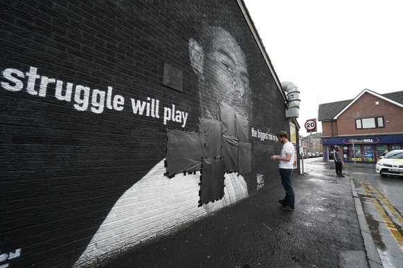 Ed Wellard, from Withington, tapes bin liners across offensive wording on the mural of Manchester United striker and England player Marcus Rashford on the wall of the Coffee House Cafe on Copson Stree ...