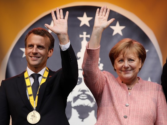 epaselect epa06725179 French President Emmanuel Macron (L) and German Chancellor Angela Merkel (R) greet on stage after the Charlemagne Prize (Karlspreis) ceremony at the town hall in Aachen, Germany, ...