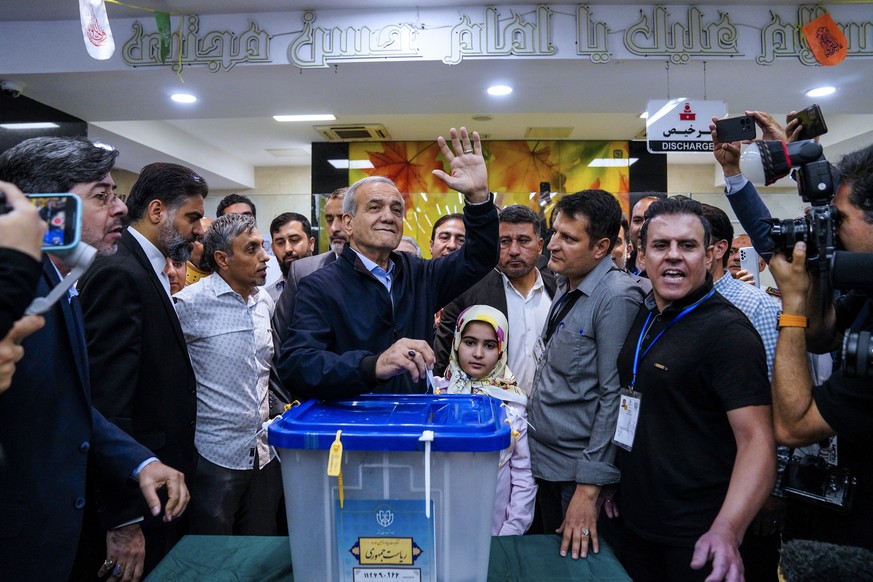 In this photo provided by Iranian Students&#039; News Agency, ISNA, reformist candidate for the Iranian presidential election Masoud Pezeshkian casts his ballot as he waves to media in a polling stati ...
