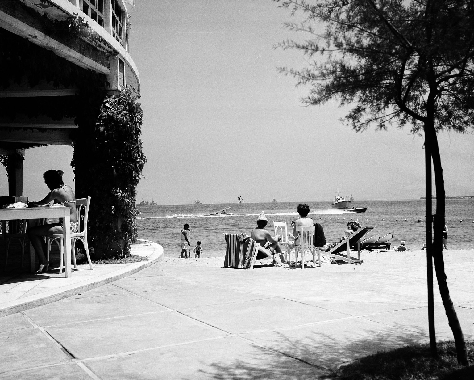 Sunbathers relax and watch water skiers on the St. George Hotel beach in Beirut, Lebanon, July 24, 1958. In the background are American warships, a grim reminder of the trouble that besets this strife ...