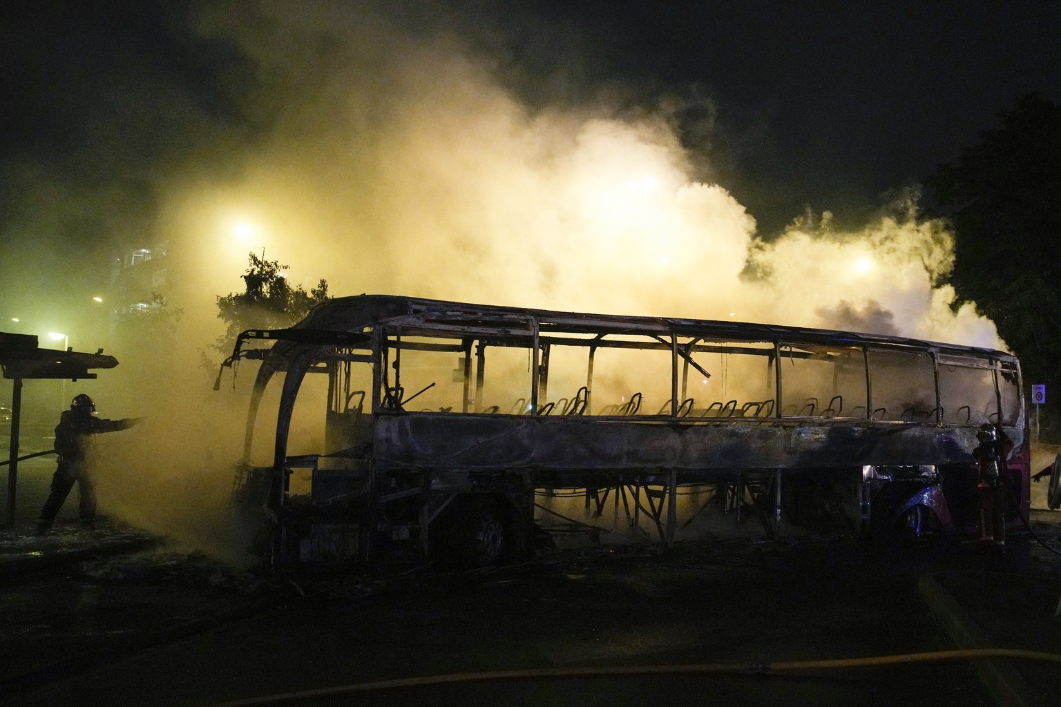 A firefighter uses a water hose on a burnt bus in Nanterre, outside Paris, France, Saturday, July 1, 2023. French President Emmanuel Macron urged parents Friday to keep teenagers at home and proposed  ...