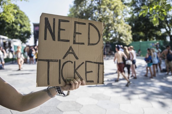 A ticket dealer holds a sign saying &quot;need a ticket&quot;, at the first day of the Gurten music open air festival in Bern, Switzerland, Thursday, July 16, 2016. (KEYSTONE/Peter Klaunzer)