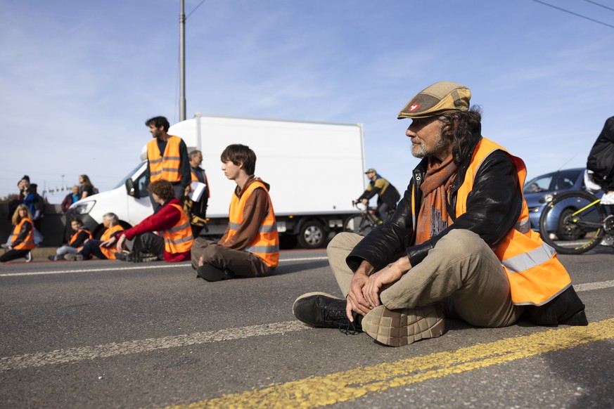 Environmental activists and members of Renovate Switzerland block the road over the Lorraine Bridge during a roadblock action in Bern, Switzerland, Saturday, October 29, 2022. (KEYSTONE/Peter Klaunzer ...