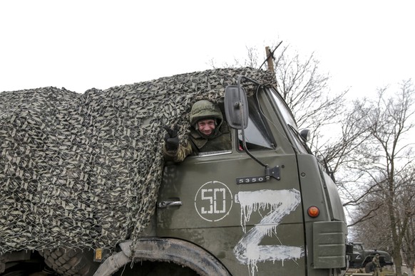 A serviceman waves from a military truck parked in a street in Mykolaivka, Donetsk region, the territory controlled by pro-Russian militants, eastern Ukraine, Sunday, Feb. 27, 2022. Fighting also rage ...
