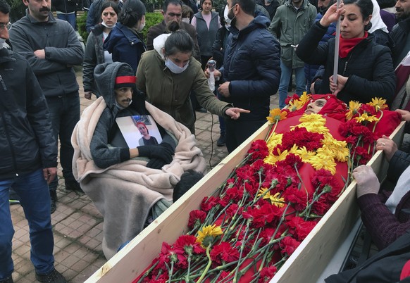 Mourners gather around the open coffin of Helin Bolek, a member of a popular folk music group that is banned in Turkey, during the funeral procession in Istanbul, Friday, April 3, 2020. Bolek died at  ...