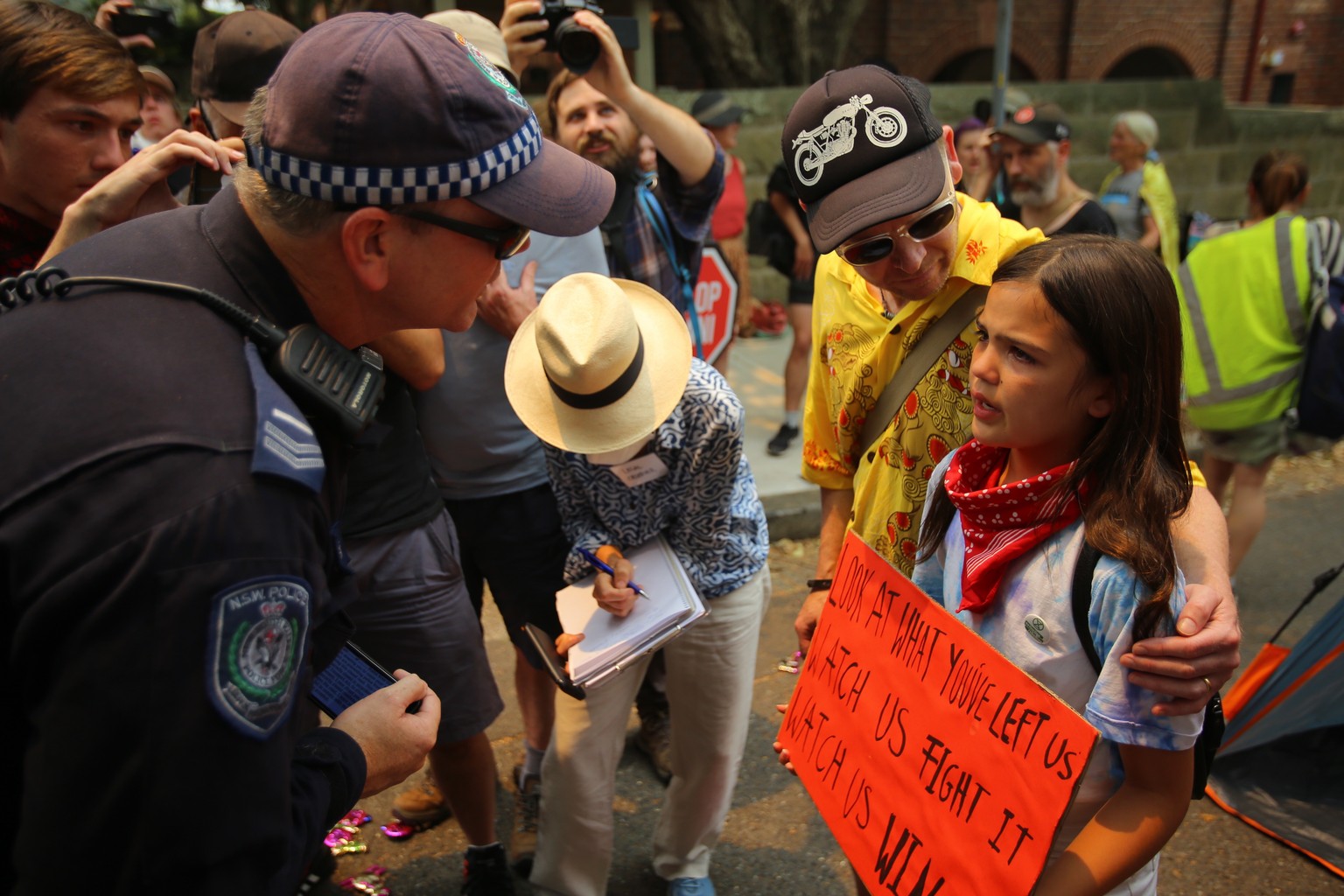 epaselect epa08080986 A policeman talks to a young girl during a protest outside Kirribilli House in Sydney, Australia, 19 December 2019. Protesters condemn Australian Prime Minister Scott Morrison� ...