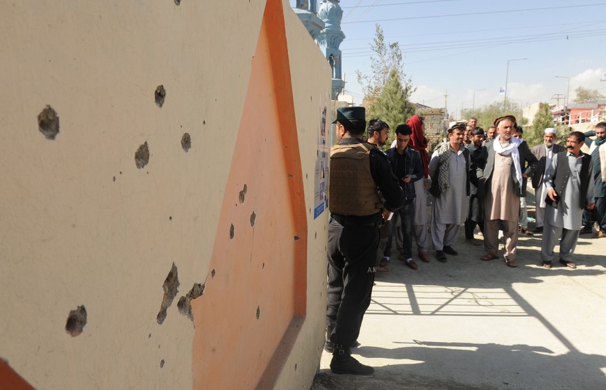 epa07108748 Landmine shrapnel damage on a wall as people stand line outside a polling center in Kabul, Afghanistan, 21 October 2018, where an explosion killed four people and injured 12 others a day e ...