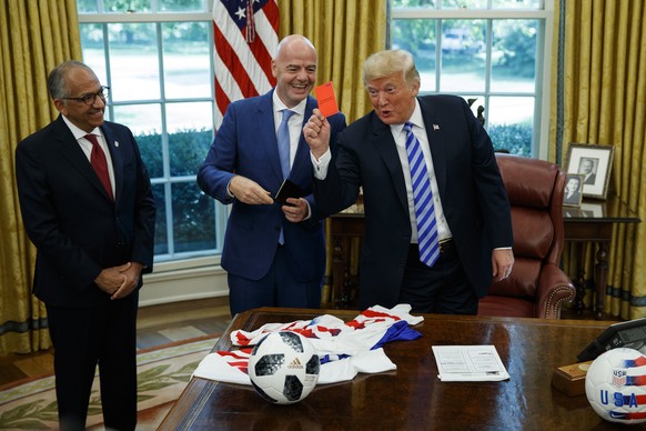 President Donald Trump holds up a red card during a meeting with FIFA president Gianni Infantino, center, and United States Soccer Federation president Carlos Cordeiro, left, in the Oval Office of the ...