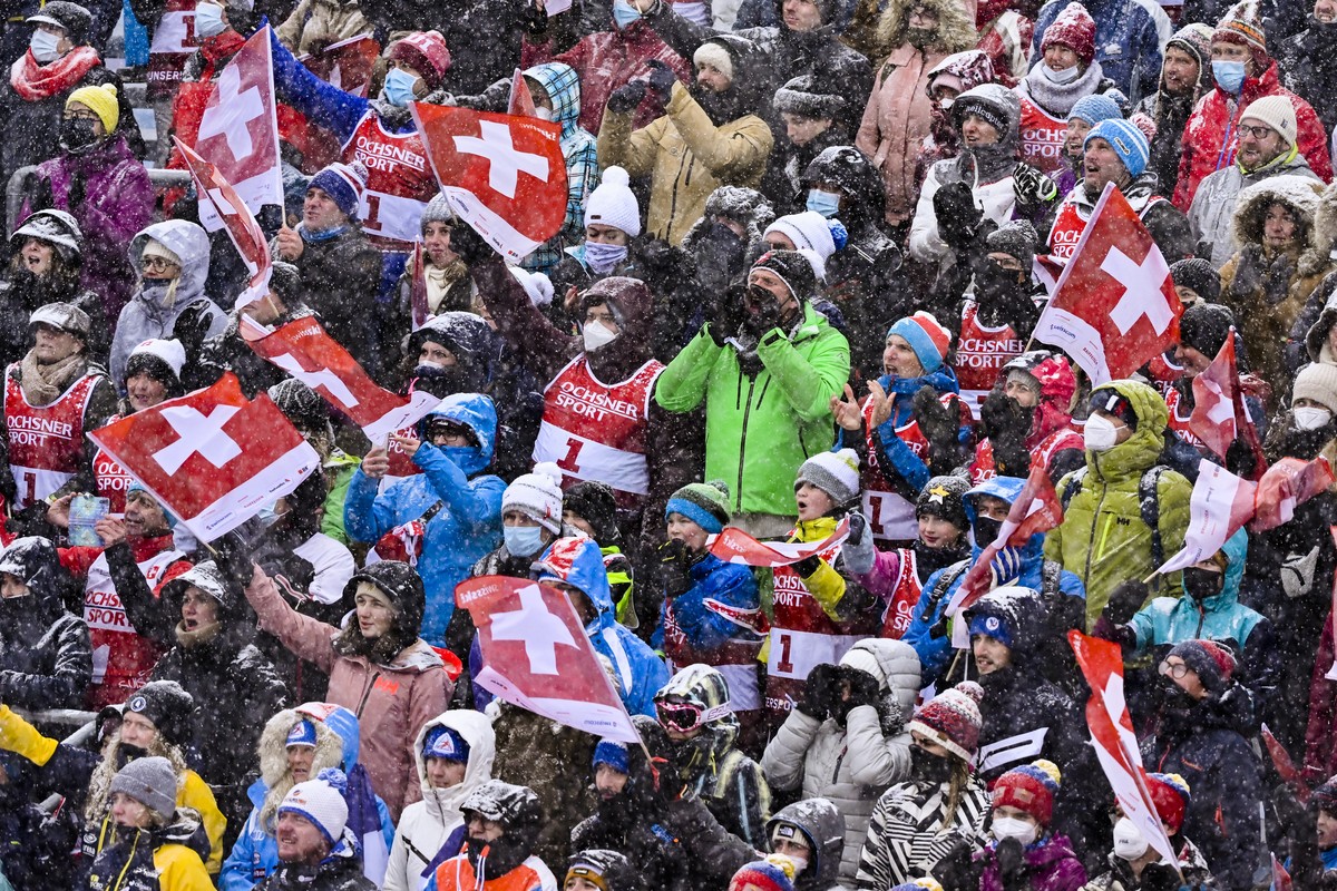 The spectators with or without protective masks stand in the finish area during the second run of the men's slalom race at the Alpine Skiing FIS Ski World Cup in Adelboden, Switzerland, Sunday, J ...
