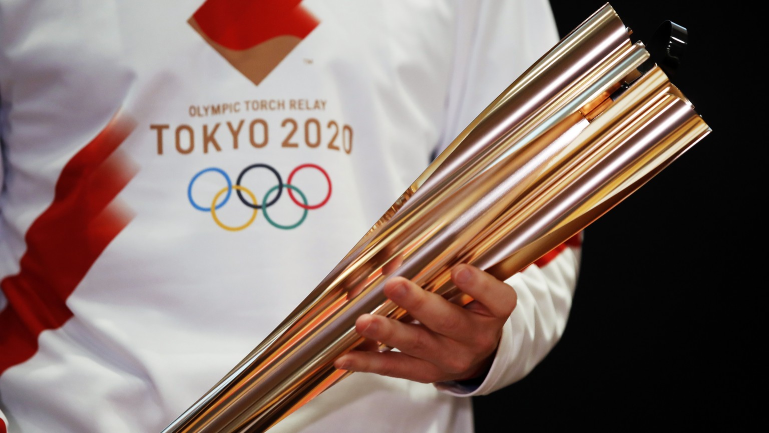 FILE - In this Feb. 24, 2020, file photo, Greek singer Sakis Rouvas wears the uniform of the torch relay runners in Athens, Greece, as he holds the torch of the 2020 Tokyo Olympic Games during a prese ...