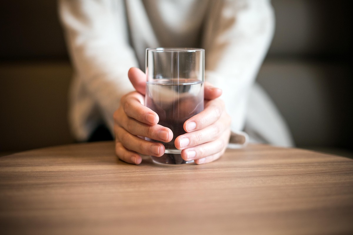 Frau hält Wasserglas.