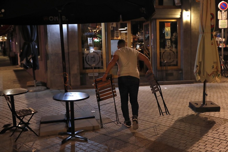 An owner of the Beers Bank pub removes chairs and tables from the terrace of the bar at the end of the day in Brussels, Wednesday, Oct. 7, 2020. Since bars in Brussels were forced to close as of Thurs ...