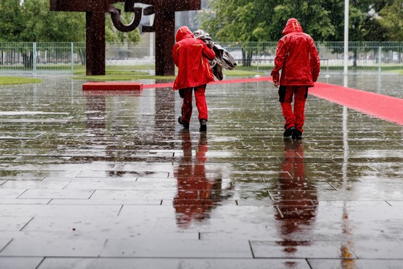 dpatopbilder - 21.07.2025, Berlin: Mitarbeiter des Bundeskanzleramtes tragen bei heftigem Regen Planen um das Podest vor dem Besuch des Ministerpr�sidenten des K�nigreichs Norwegen abzudecken. Foto: C ...