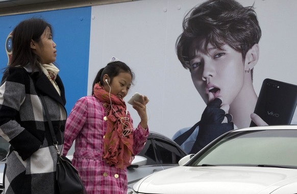 FILE - In this Oct. 21, 2017, file photo, Chinese women walk past advertisement featuring teen idol Lu Han, also known as China&#039;s Justin Bieber in Beijing. China&#039;s government banned effemina ...