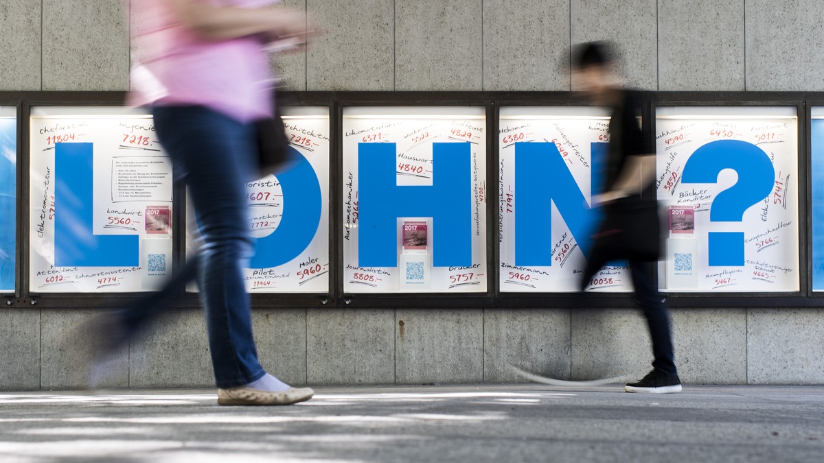 Menschen bewegen sich vor einem Plakat mit der Aufschrift "Lohn?", aufgenommen am Donnerstag, 6. Juli 2017 in Zuerich. (KEYSTONE/Ennio Leanza)