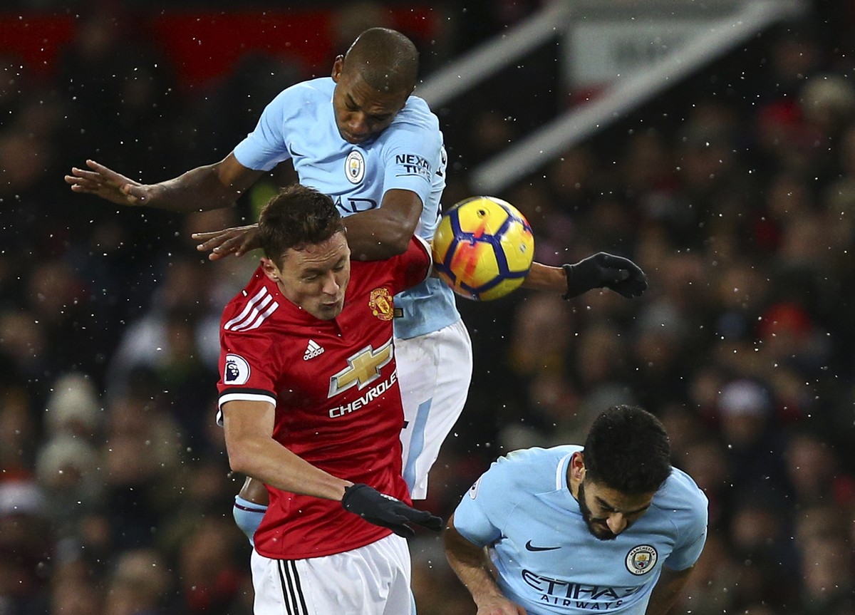 Manchester United's Nemanja Matic, left, jumps for the ball with Manchester City's Fernandinho and Ilkay Gundogan, right, during the English Premier League soccer match between Manchester Un ...