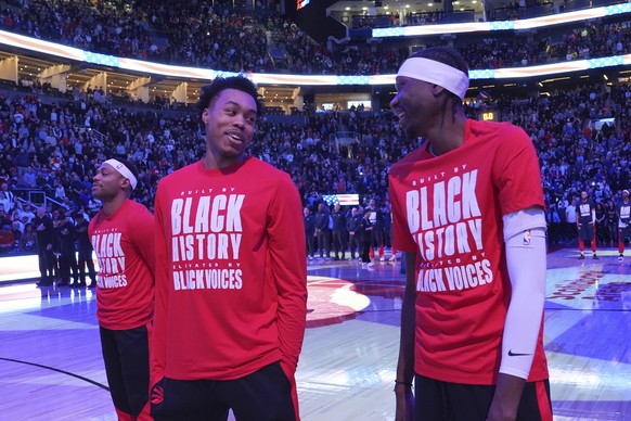 From left to right, Toronto Raptors forwards Bruce Brown, Scottie Barnes and Chris Boucher react as fans boo the United States national anthem before NBA basketball game action against the Los Angeles ...