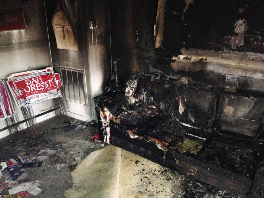 A burned couch is shown next to warped campaign signs at the Orange County Republican Headquarters in Hillsborough, NC on Sunday, Oct. 16 2016. Someone threw flammable liquid inside a bottle through a ...