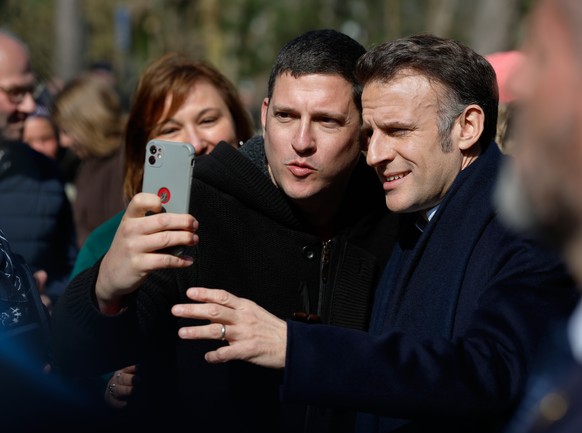 epa12821328 French President Emmanuel Macron poses for a selfie as he arrives at the voting station for the first round of Frances municipal elections in Le Touquet-Paris-Plage, northern France, 15 M ...