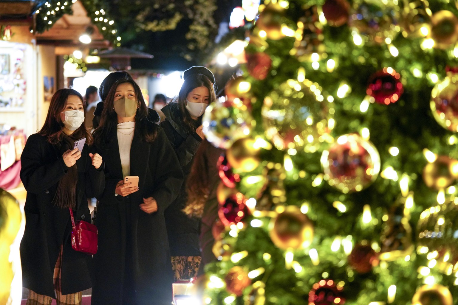 epa08887063 Office workers wearing protective masks enjoy their time at a Christmas market in Tokyo, Japan, 16 December 2020, after Tokyo government announced it marked highest record of 678 new COVID ...