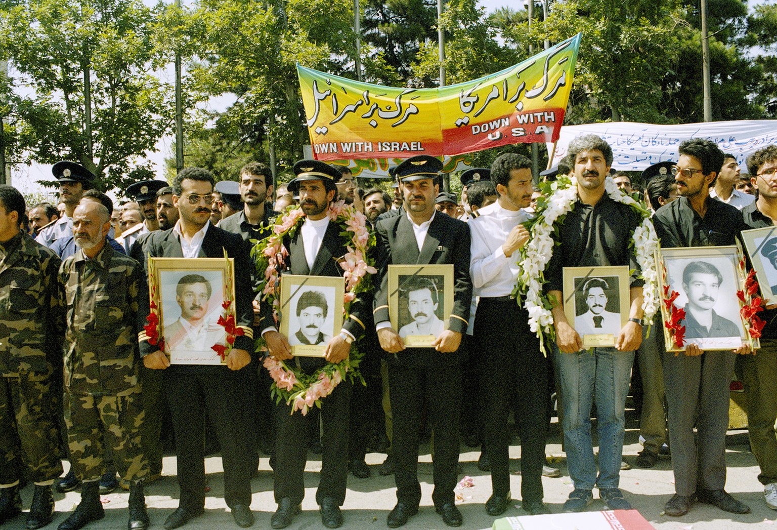 Employees of Iran Air hold photographs of the crew aboard the Iran Air Airbus that was shot down by the U.S. Navy, July 7, 1988, in Tehran. Thousands of Iranians participated in a mass funeral for 76  ...
