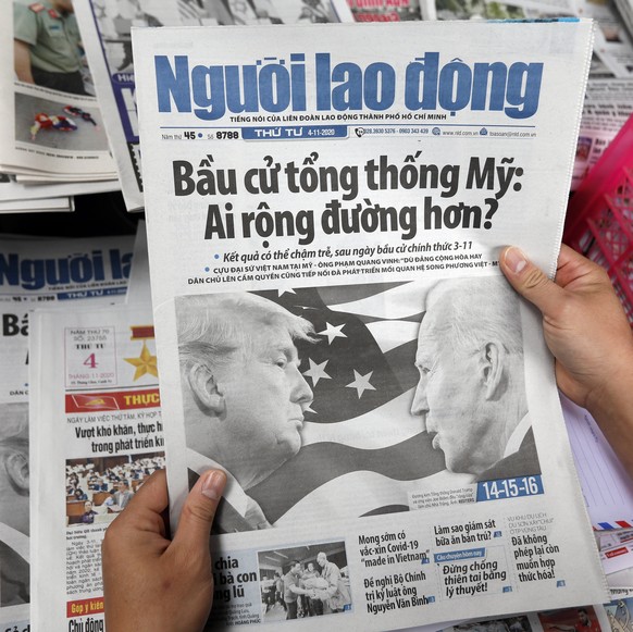 epa08797513 A man picks up a newspaper featuring an article about the US presidential election on the front page at a newsstand in Hanoi, Vietnam, 04 November 2020. The United States held its presiden ...