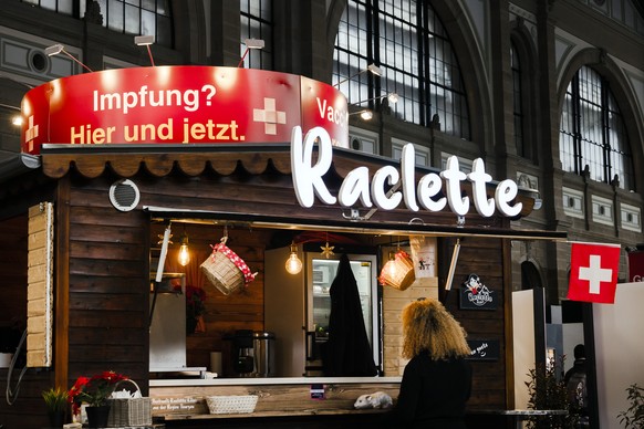 Eine Frau verpflegt sich am Raclette Stand im Impfdorf in der grossen Halle des Hauptbahnhofs Zuerich, am Montag, 8. November 2021 in Zuerich. (KEYSTONE/Michael Buholzer)