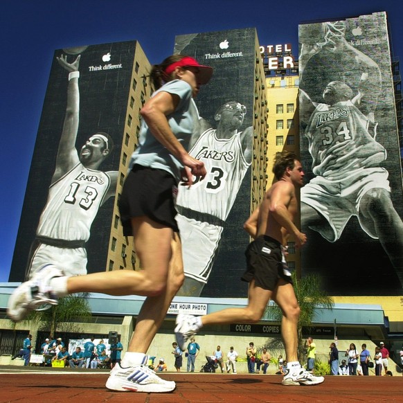 A pair of marathon runners pass by building-sized murals of Los Angeles Lakers stars, from left, Wilt Chamberlain, Kareem Abdul-Jabbar and Shaquille O'Neal on Olympic Boulevard as they near the finish ...