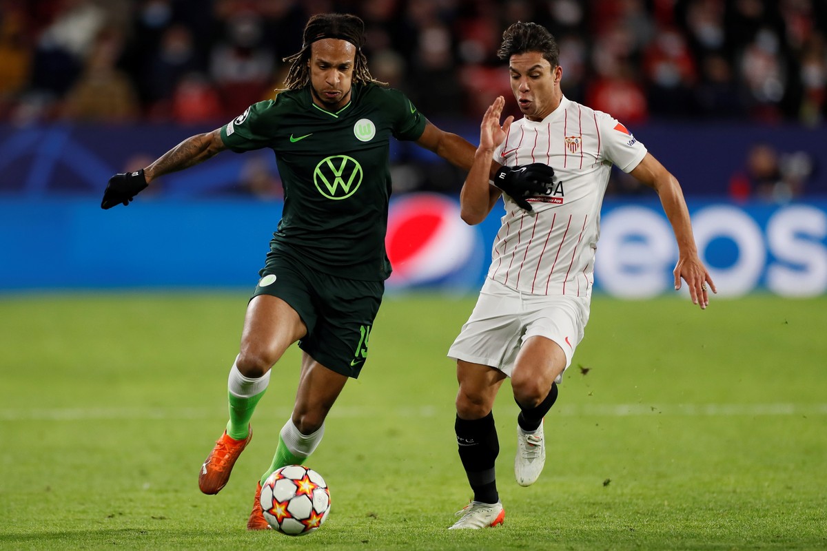 epa09599872 Wolfsburg's midfielder Kevin Mbabu (L) in action against Sevilla's Oliver Torres (R) during the UEFA Champions League match played in Ramon Sanchez Pizjuan stadium in Sevilla, so ...