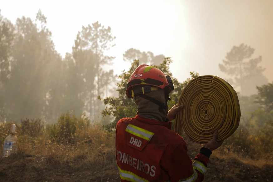 epa10064283 A firefighter handles his gear during the fire in Cruzinha, Alvaiazere, Portugal, 10 July 2022. The fire that has been burning in forest stands since 07 July in Cumeada, Ourem, remains act ...