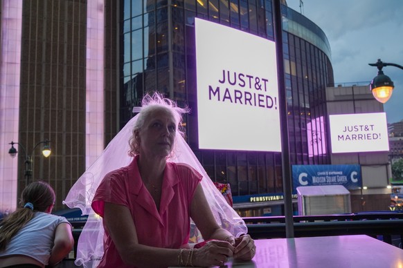 A Taylor Swift fan wearing a wedding veil sits at a restaurant next to Madison Square Garden where a "JUST&amp;T MARRIED" sign is displayed during a wedding between singer Taylor Swift and N ...