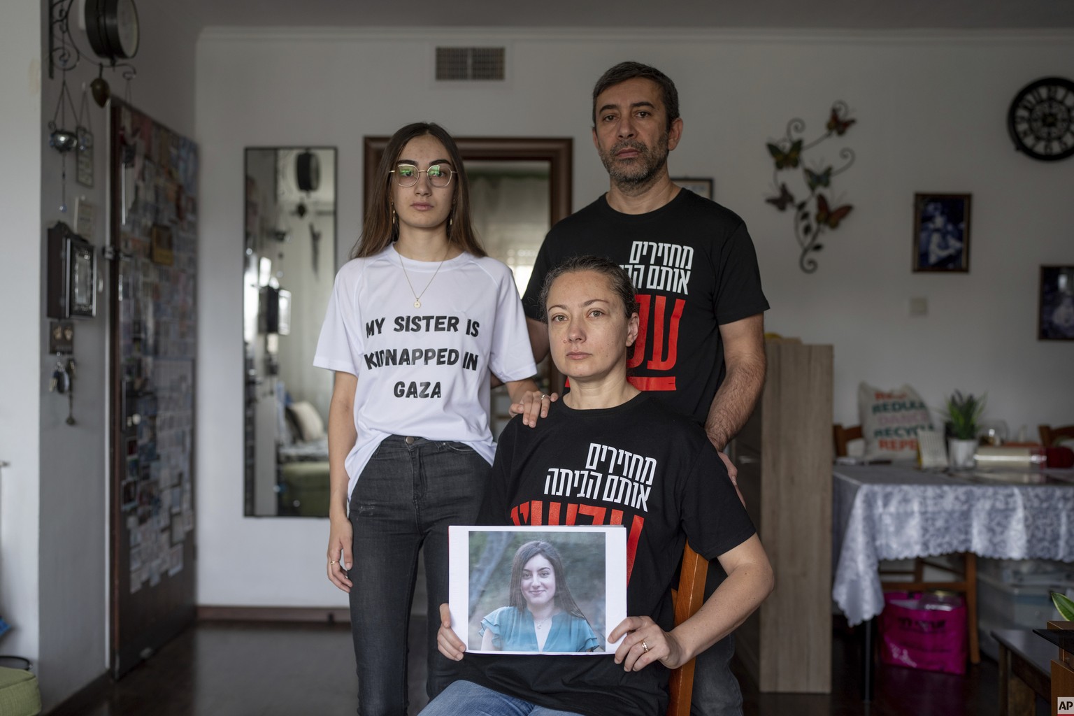 The Ariev family, parents Albert and Ira and their daughter Sasha, hold a portrait of young soldier Karina Ariev at their family home in Jerusalem, Sunday, Oct. 29, 2023.  Ariev, an Israeli soldier ...