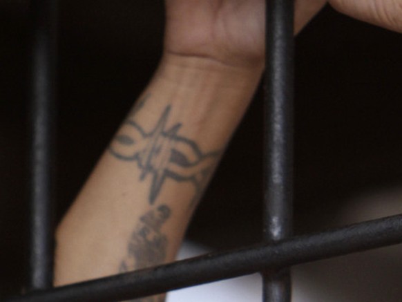 Behind bars, a Mara Salvatrucha gang member attends a mass celebrated by Archbishop Luigi Pezzuto, Apostolic Nuncio to El Salvador, and head army and police chaplain Monsignor Fabio Colindres at a pri ...