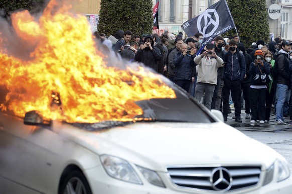 Protesters watch a burning car during a demonstration on Thursday, April 13, 2023 in Rennes, western France.  Protesters oppose President Emmanuel Macron's unpopular plan to raise retirement age...