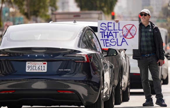 A protester holds a sign reading &quot;SELL THAT TESLA&quot; in front of a Tesla driver during a rally outside a Tesla dealership in San Francisco, Saturday, March 15, 2025. (AP Photo/Josh Edelson)
AP ...
