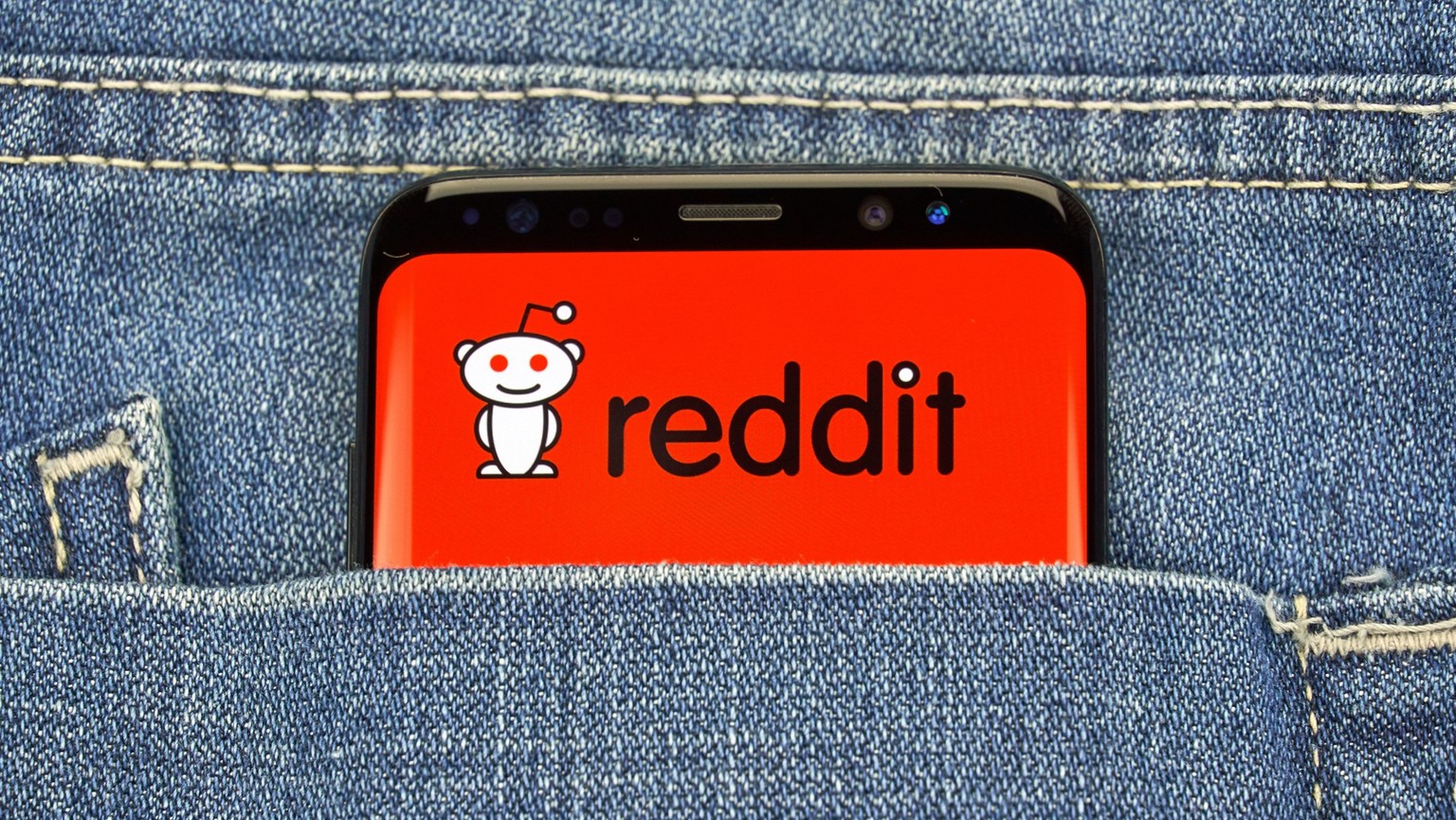 Smartphone mit Reddit-Logo in Hosentasche.