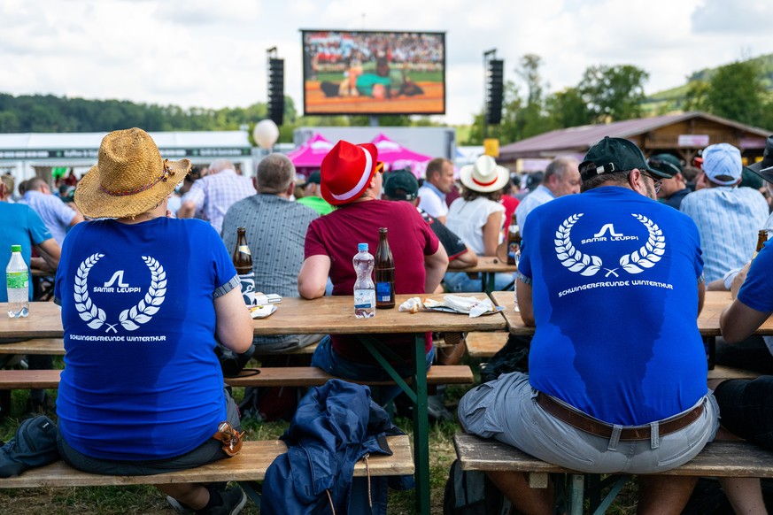 Personen im Public Viewing verfolgen das Geschehen auf einem Bildschirm am Eidgenoessischen Schwing und Aelplerfest (ESAF), am Samstag, 27. August 2022, in Pratteln. (KEYSTONE/Peter Schneider)