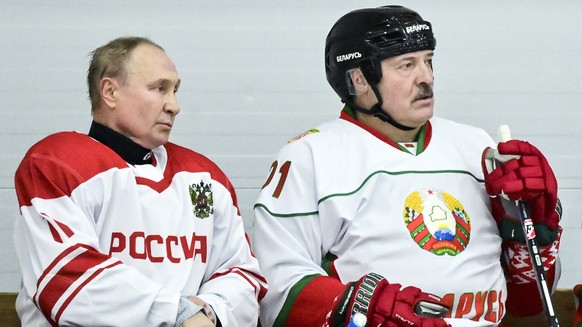 Russian President Vladimir Putin, left, and Belarusian President Alexander Lukashenko take a pause during the Night Hockey League match following their talks in Strelna, outside St. Petersburg, Russia ...