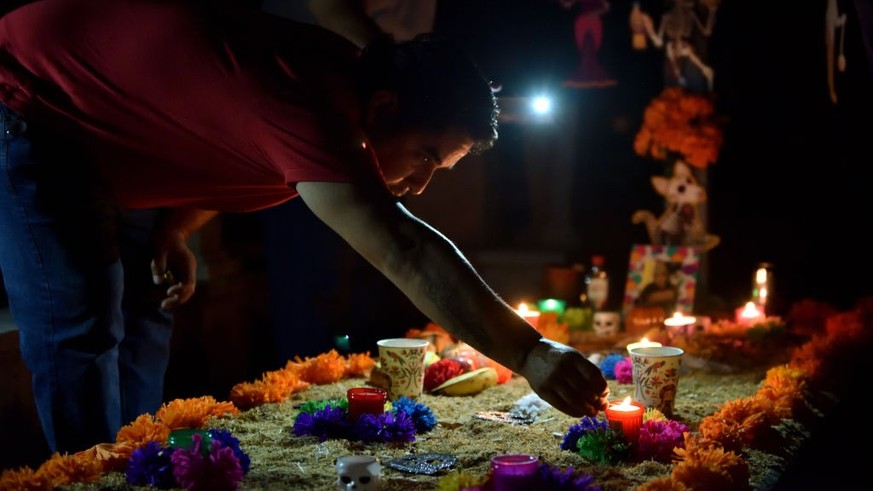 COLIMA, MEXICO - NOVEMBER 01: A woman lights a candle on a grave during &#039;Day of the Dead&#039; celebrations at Colima Municipal cemetery on November 1, 2022 in Colima, Mexico. Considered one of t ...