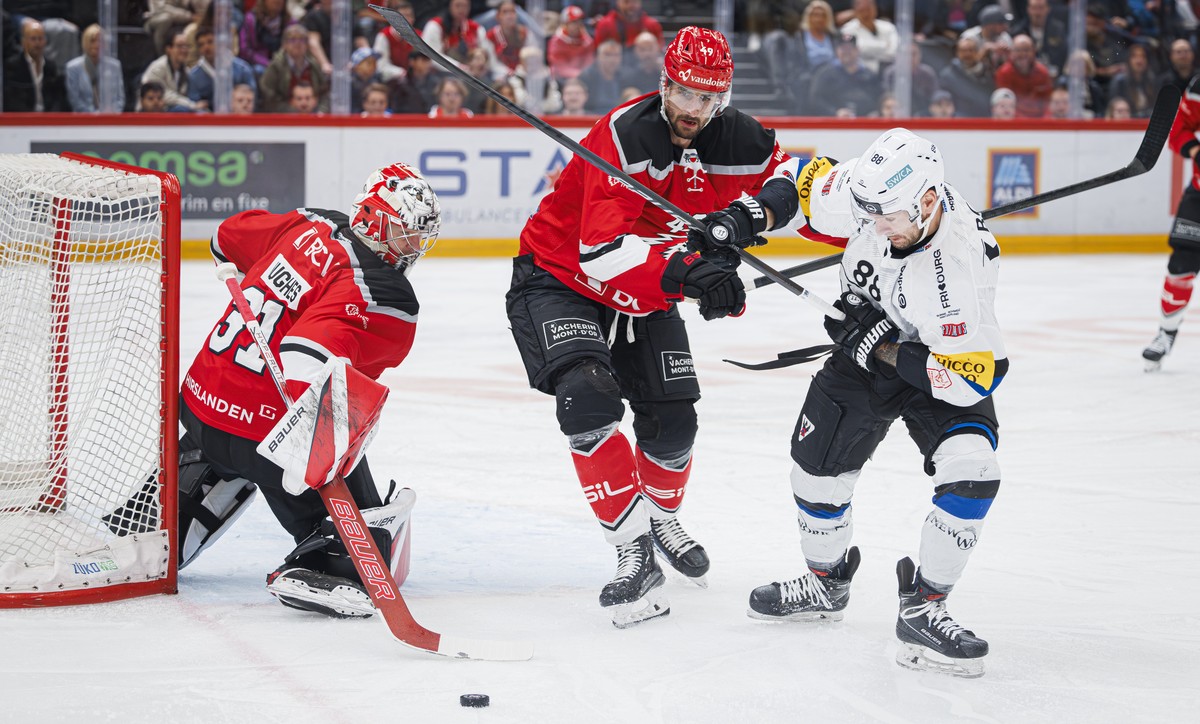 L'attaquant lausannois Cody Almond, centre, lutte pour le puck avec l'attaquant du fribourg Christopher DiDomenico, droite, lors de l'acte 4 des demi-finales des play-off du championnat ...