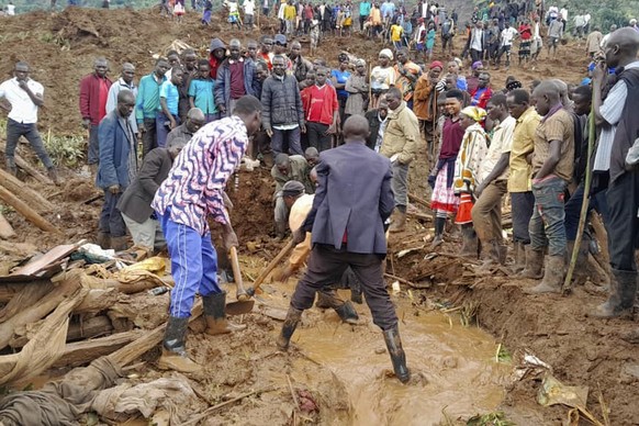 Rescue workers and people search for bodies after landslides following heavy rains buried 40 homes in the mountainous district of Bulambuli, eastern Uganda, Thursday, Nov. 28. 2024. (AP Photo/Jean Wat ...